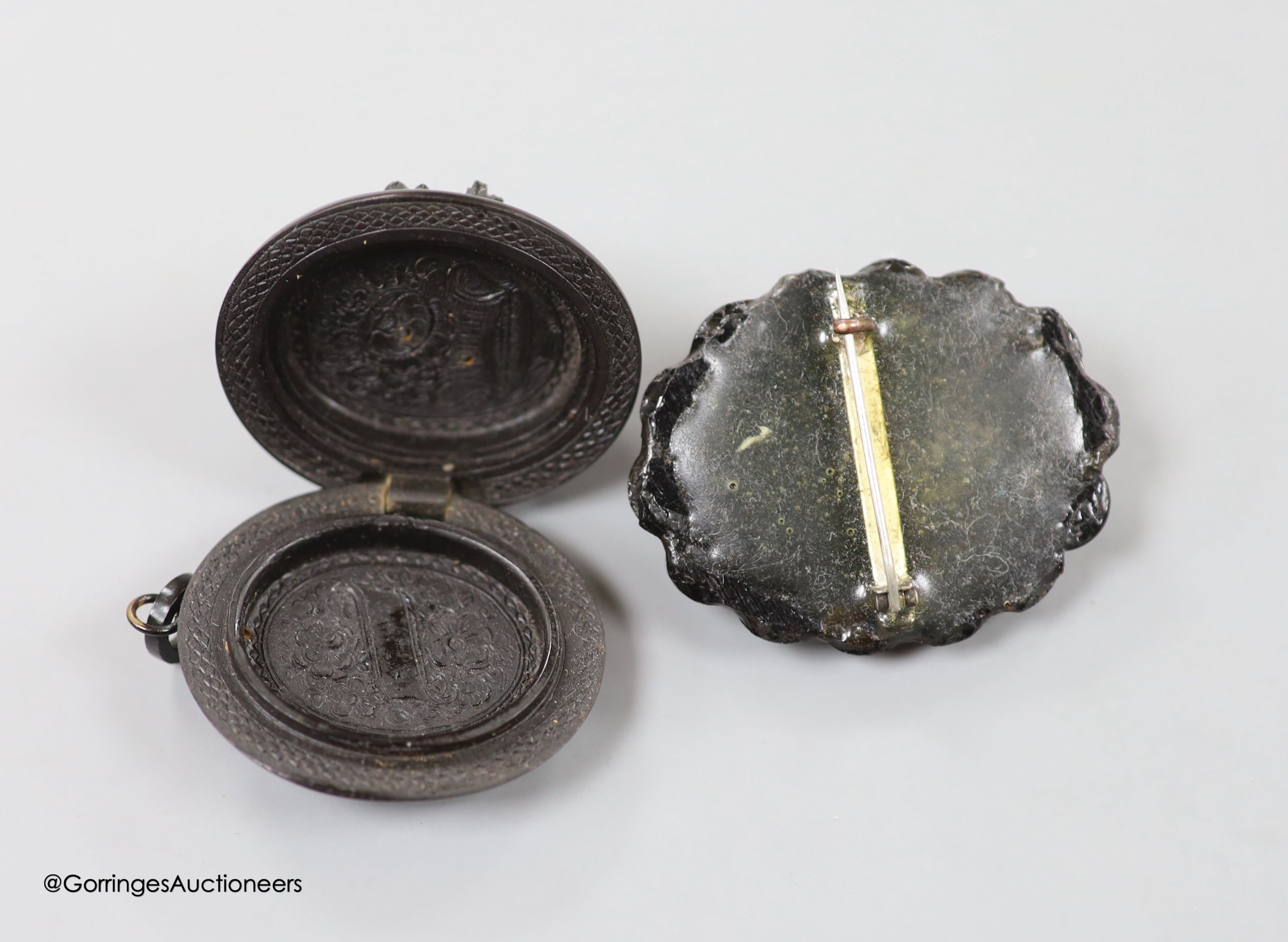 A jet oval pendant, carved with a bunch of flowers, 41mm and a similar brooch, carved with the bust of a lady.